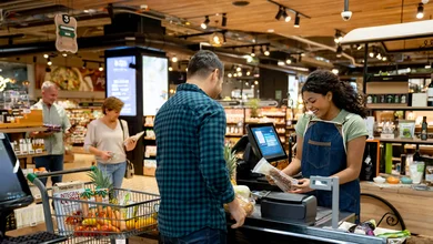 Ein Mann steht an einer Supermarktkasse und bezahlt seinen Einkauf.