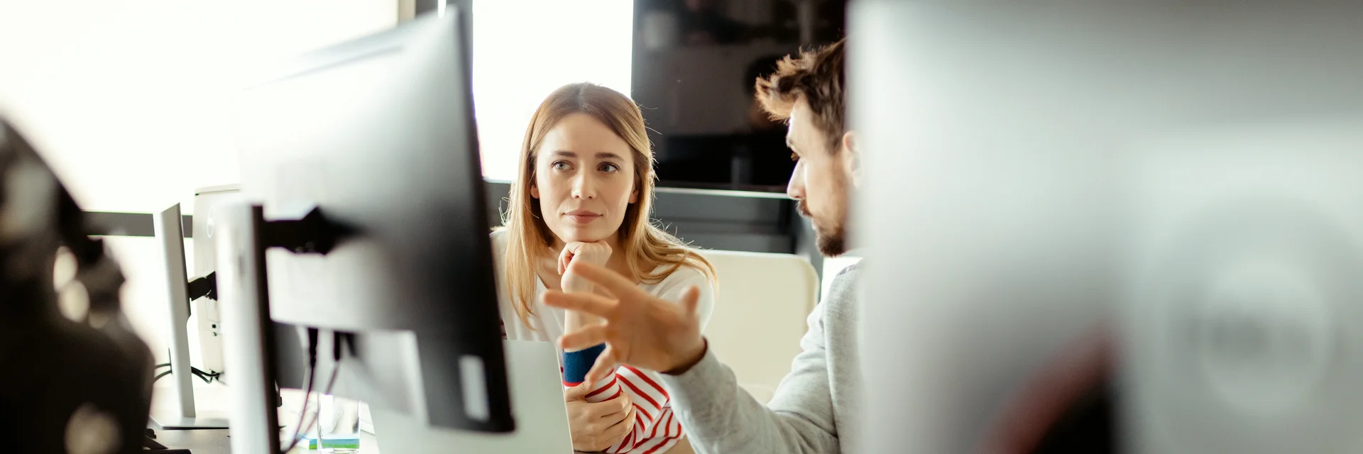 Eine Frau und ein Mann sind diskutierend durch die Lücke zwischen zwei Bildschirmen zu sehen